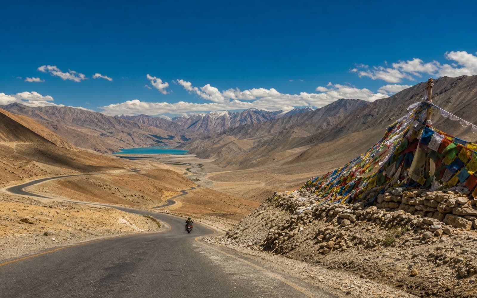 Ladakh high-pass road with prayer flags and cold desert mountains